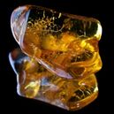 An amber crystal on a black reflective background