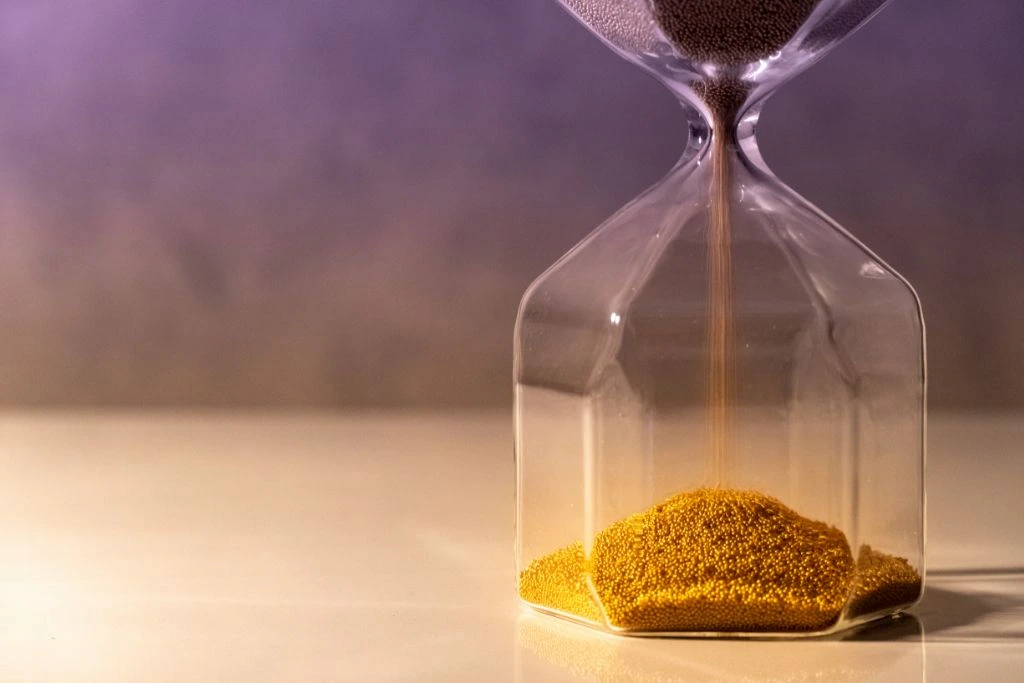 The sand is falling down to the bottom part of the hourglass