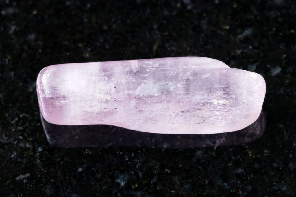 A kunzite crystal on a black granite