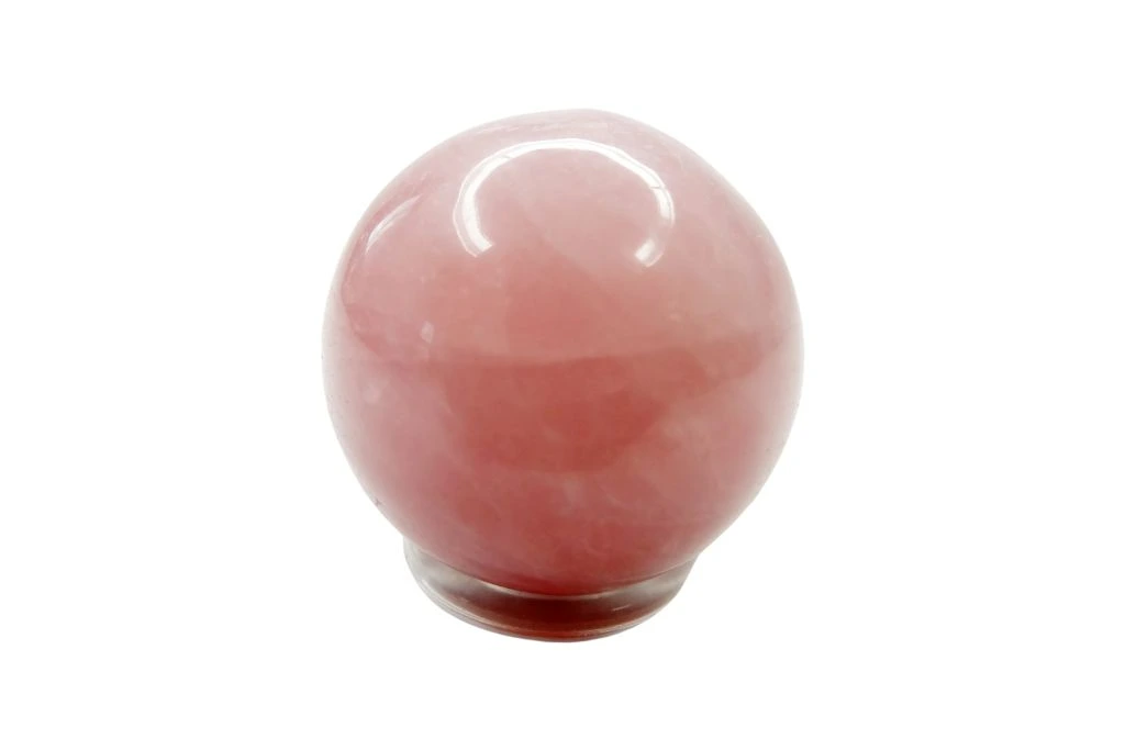 A pink quartz sphere crystal on a white background
