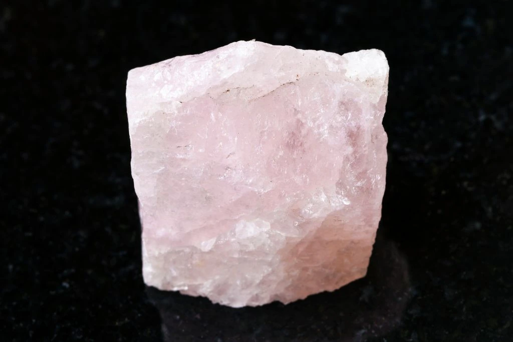 A raw morganite crystal on a black granite