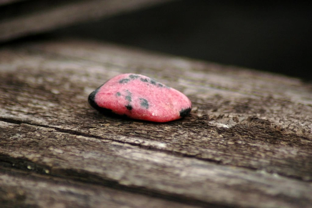 rhodonite crystal on top a wood