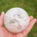 a person holding a a ball shaped selenite crystal