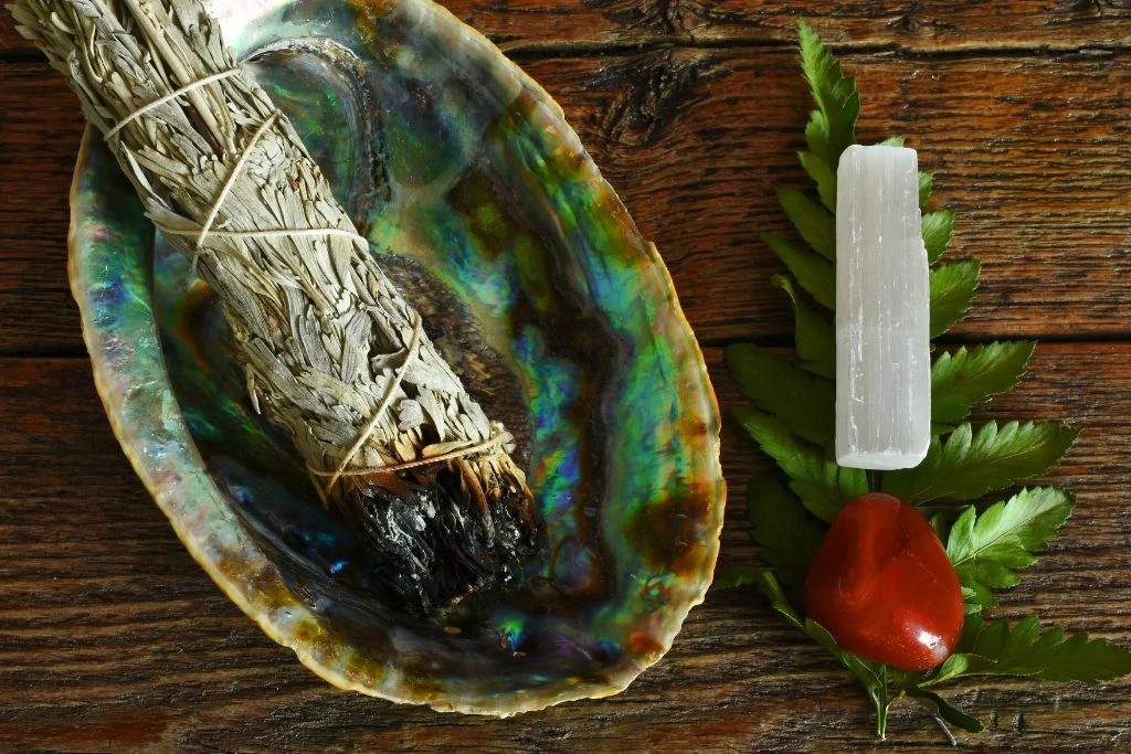 A burned white sage beside a selenite wand