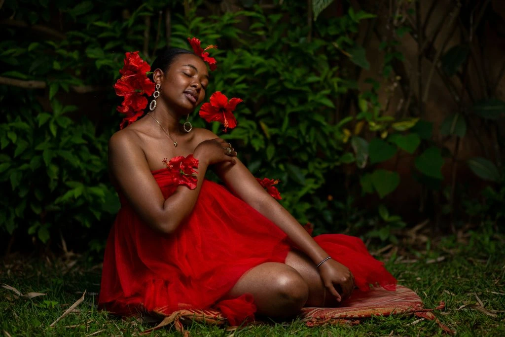 Woman wearing red dress in forest sitting on red textile 