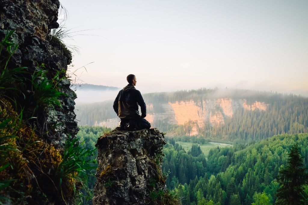 A man kneeling on top of the mountain