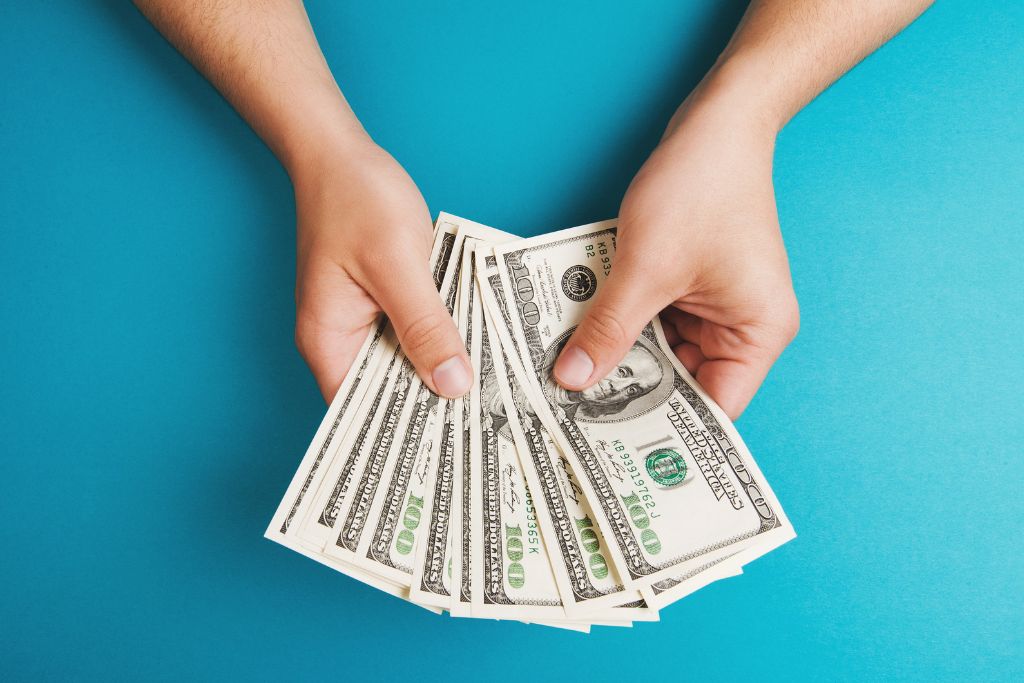 A person is holding a lot of money on a bluish background