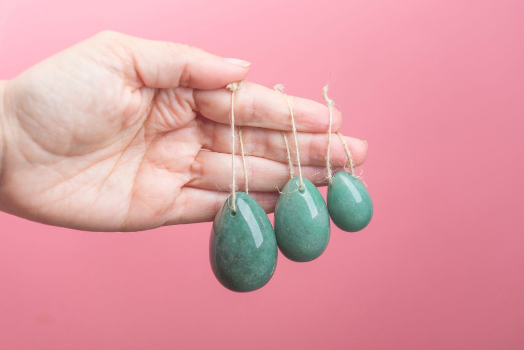 Different sizes of Yoni eggs that are hanging on a hand of a person