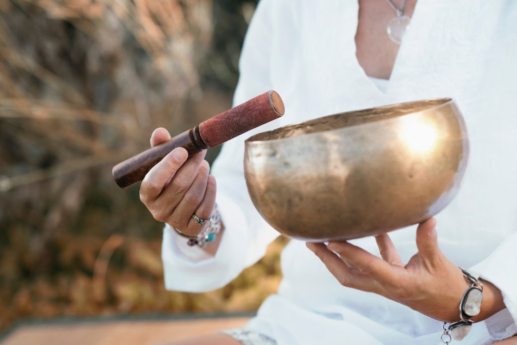 A person is holding a singing bowl and a mallet