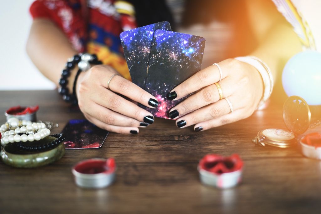 A psychic holding two tarot cards at the table