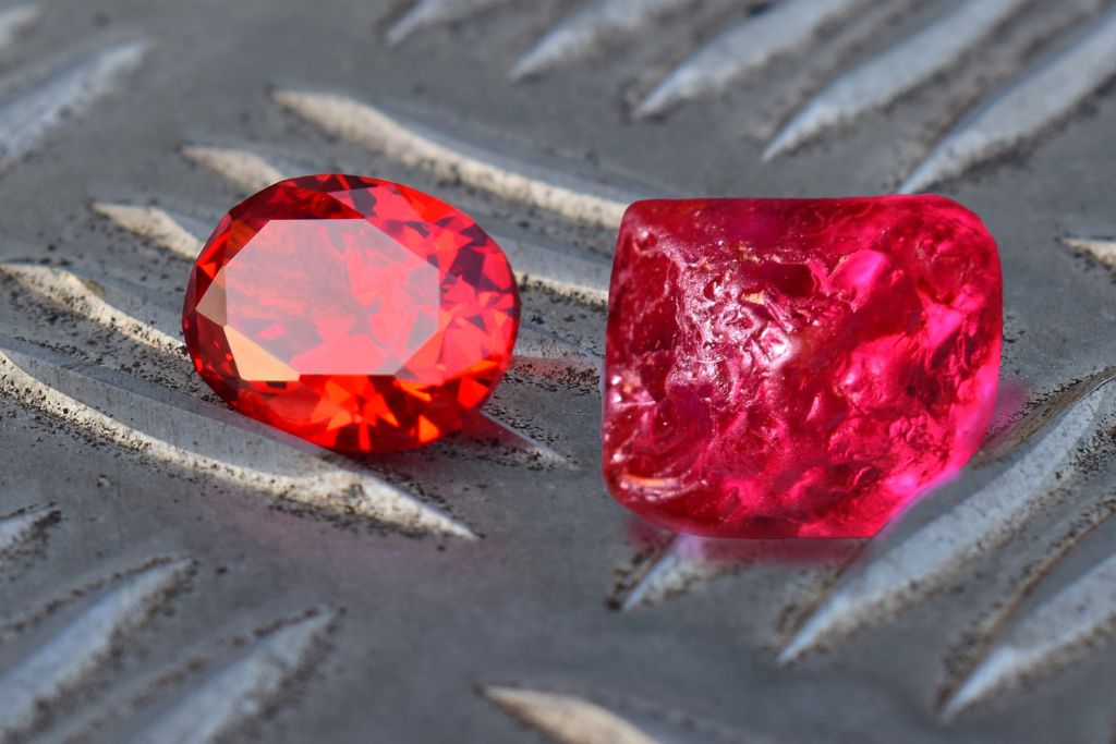A raw and polished ruby on a metal plate