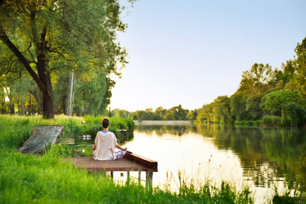 A woman meditating on a dock in nature