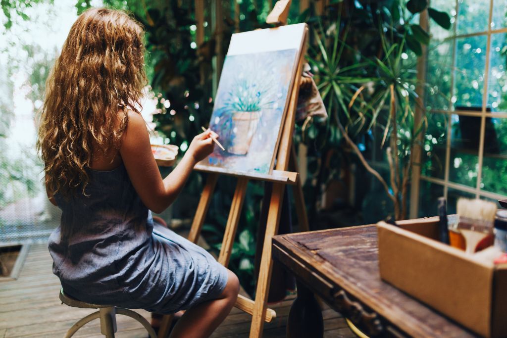 A woman painting on a canvass in a room