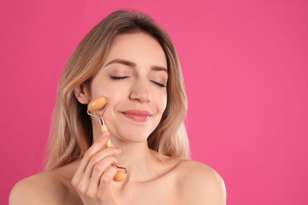 A woman is using a crystal face roller on her face