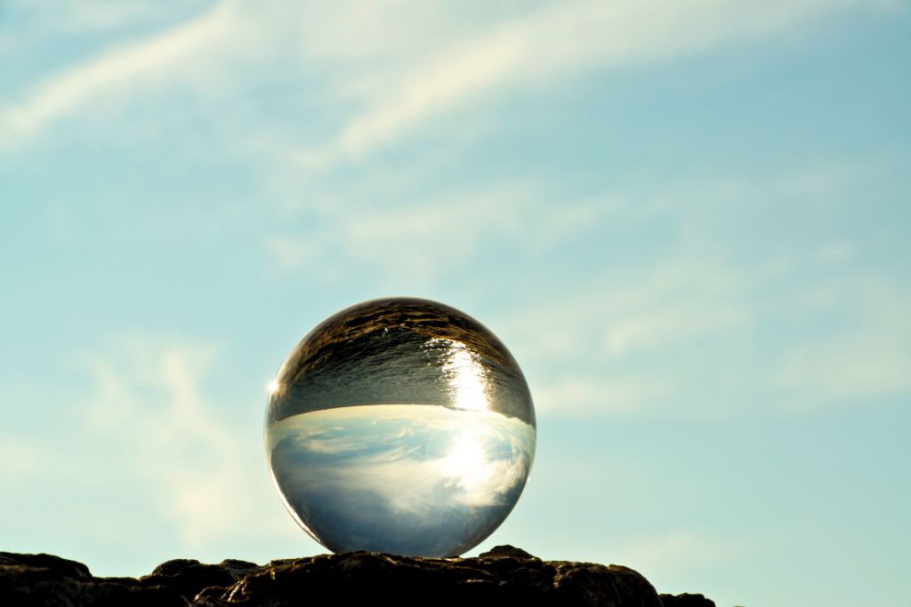 crystal ball is placed on a rock against a blue sky background
