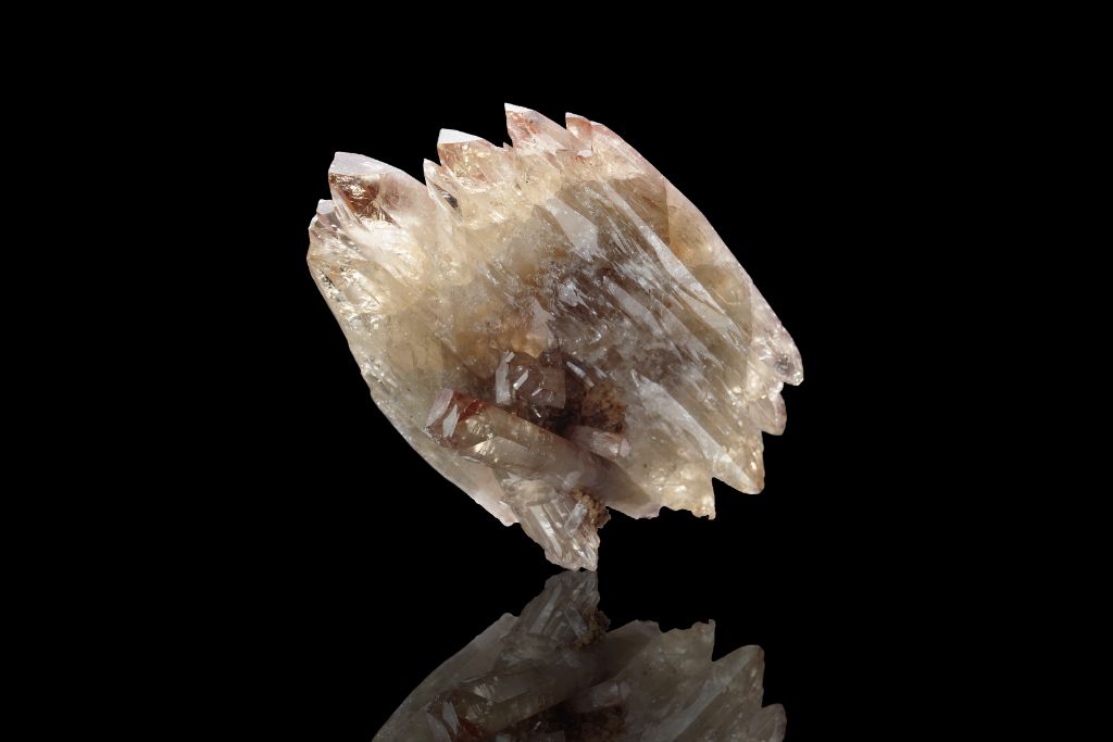 A barite crystal on a black reflective background