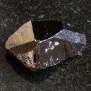 A Cassiterite crystal on a black granite