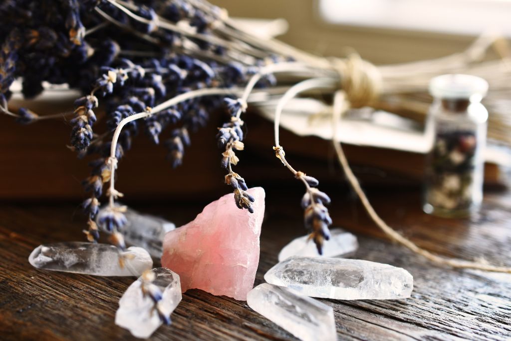 Clear Quartz crystals circling a Rose Quartz for cleansing with a Lavender plant in its background
