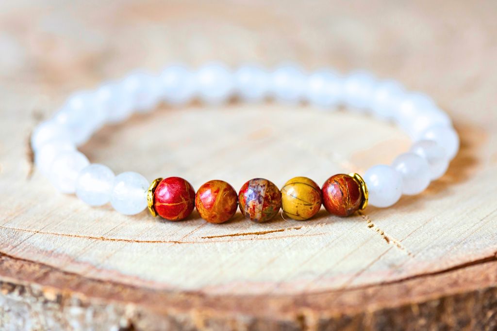 a white bracelet with five brown crystal beads at the front placed on a wooden platform