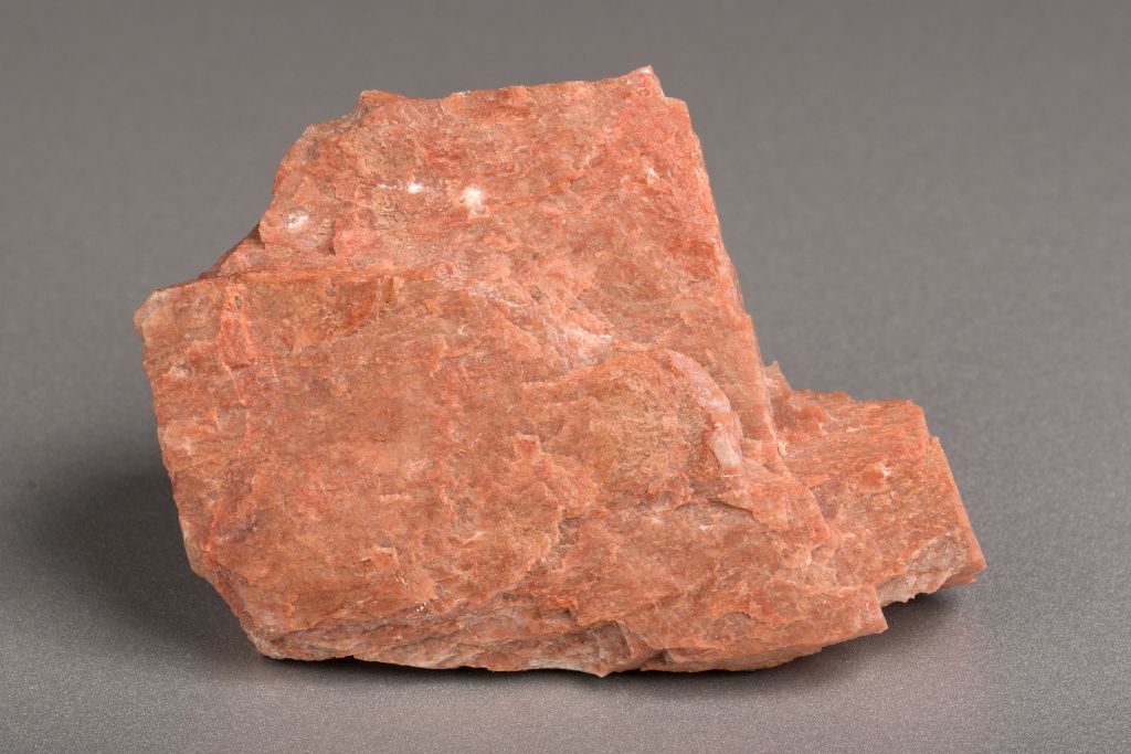 A raw feldspar crystal on a greyish background