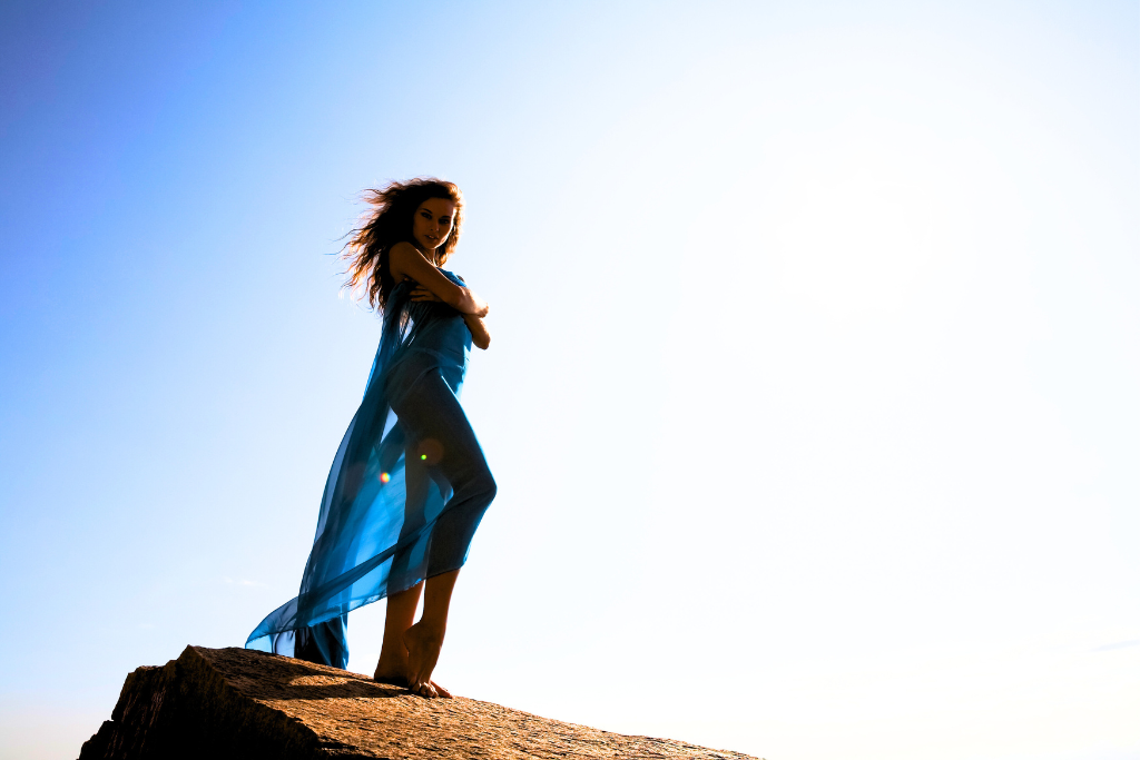 a woman posing on the top of a big brown rock