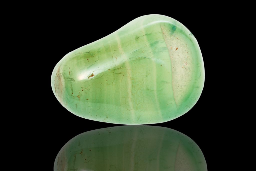 A green agate crystal on a black reflective background