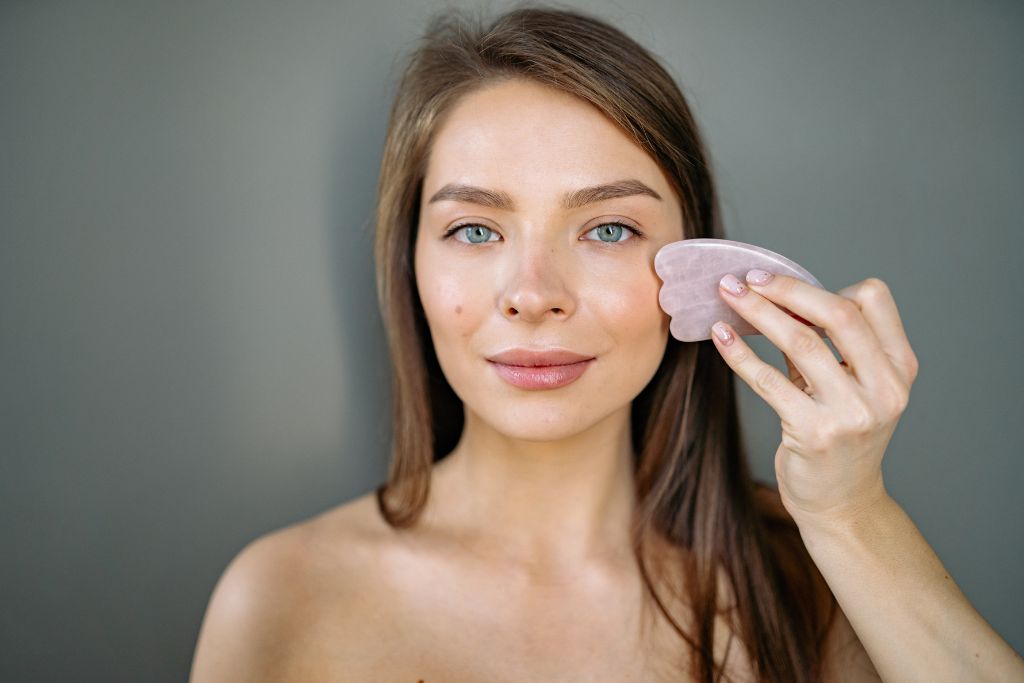 A woman doing a gua sha facial massage