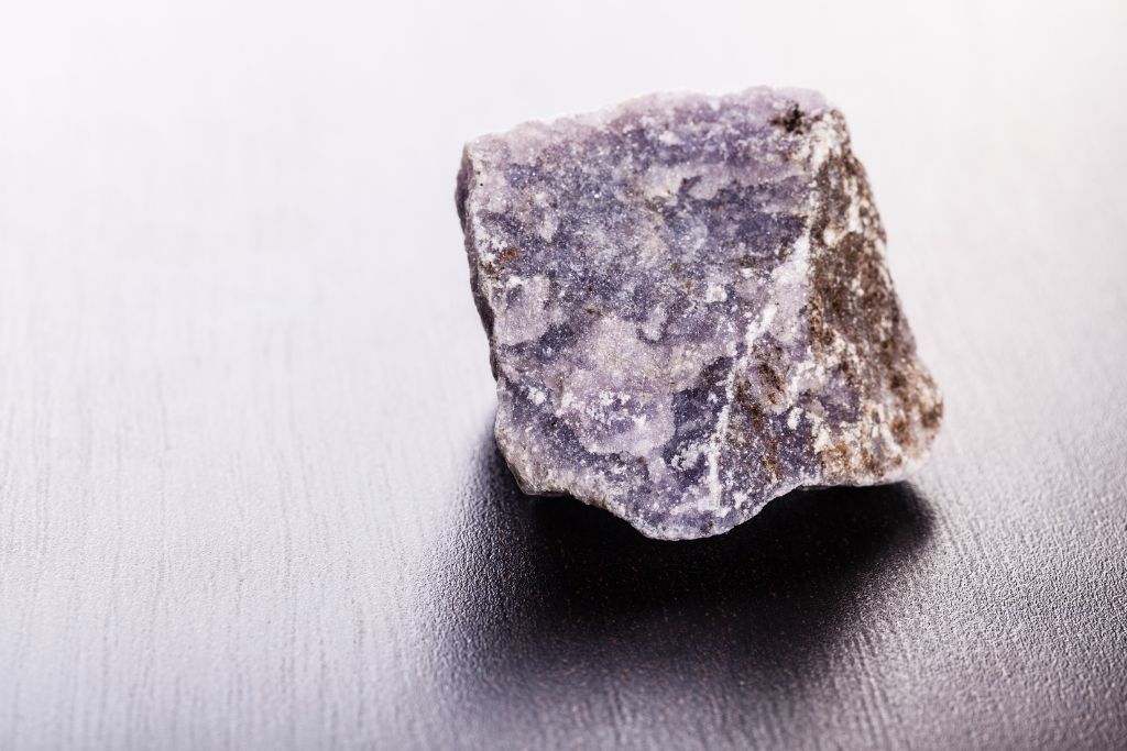 A raw lepidolite crystal on the table