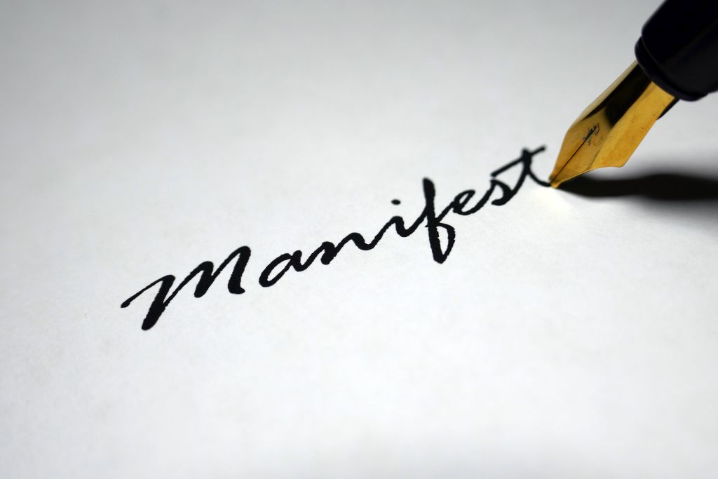 A person wrote the manifest word on a paper