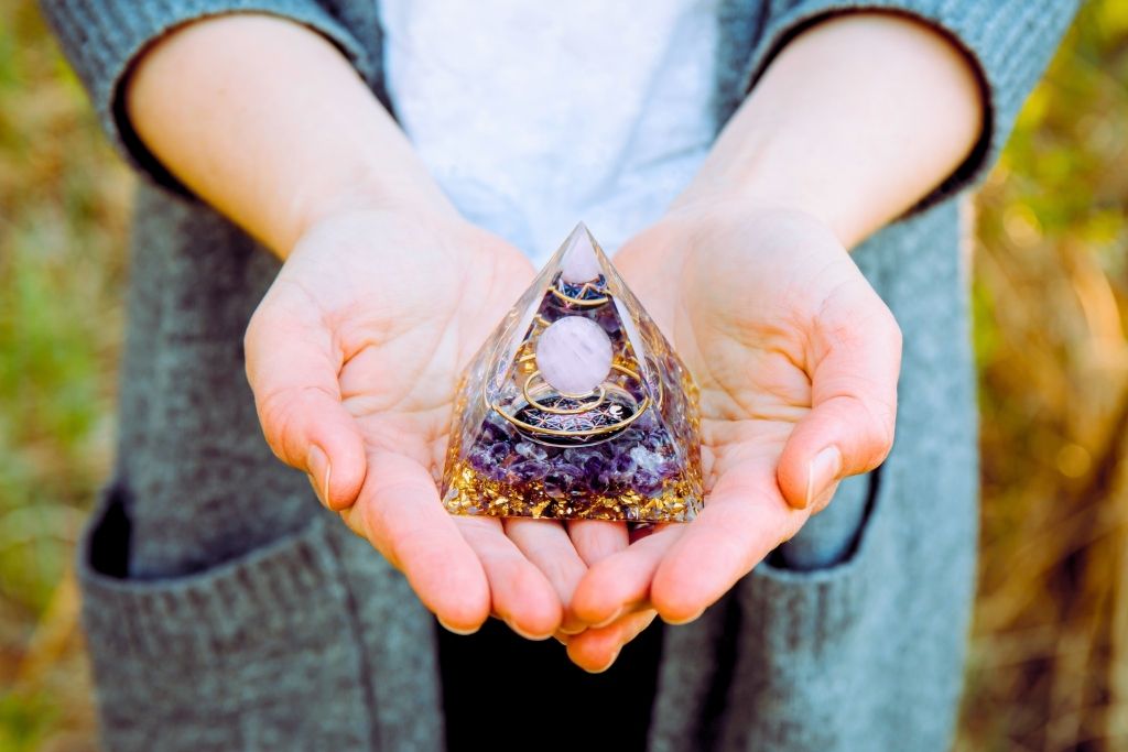 An orgone pyramid placed on the palm of a woman's hand