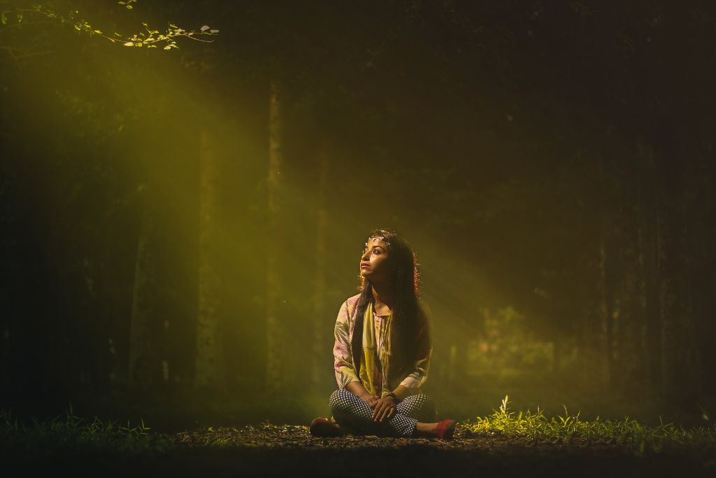 A peaceful woman in forest sitting under the sun's ray