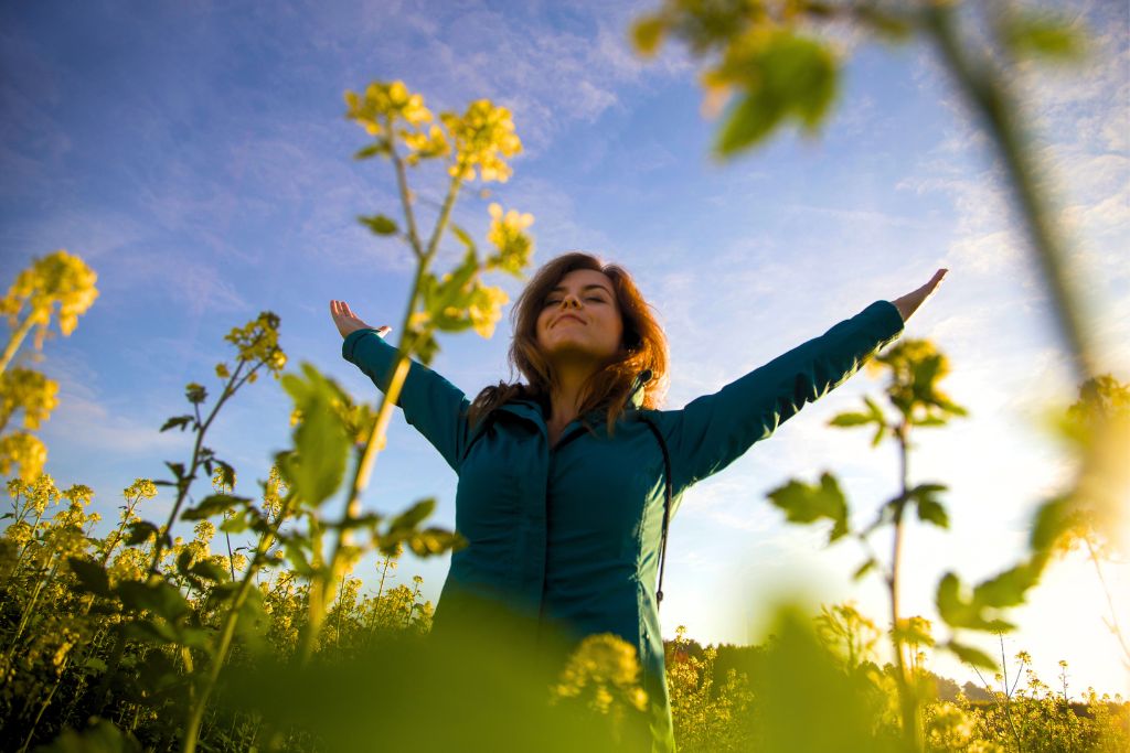 woman enjoying the nature surrounded by yellow flowers