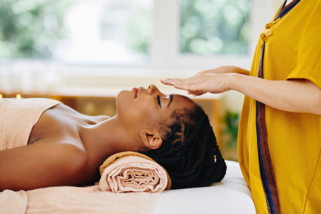 Woman laying and having a reiki healing from an expert