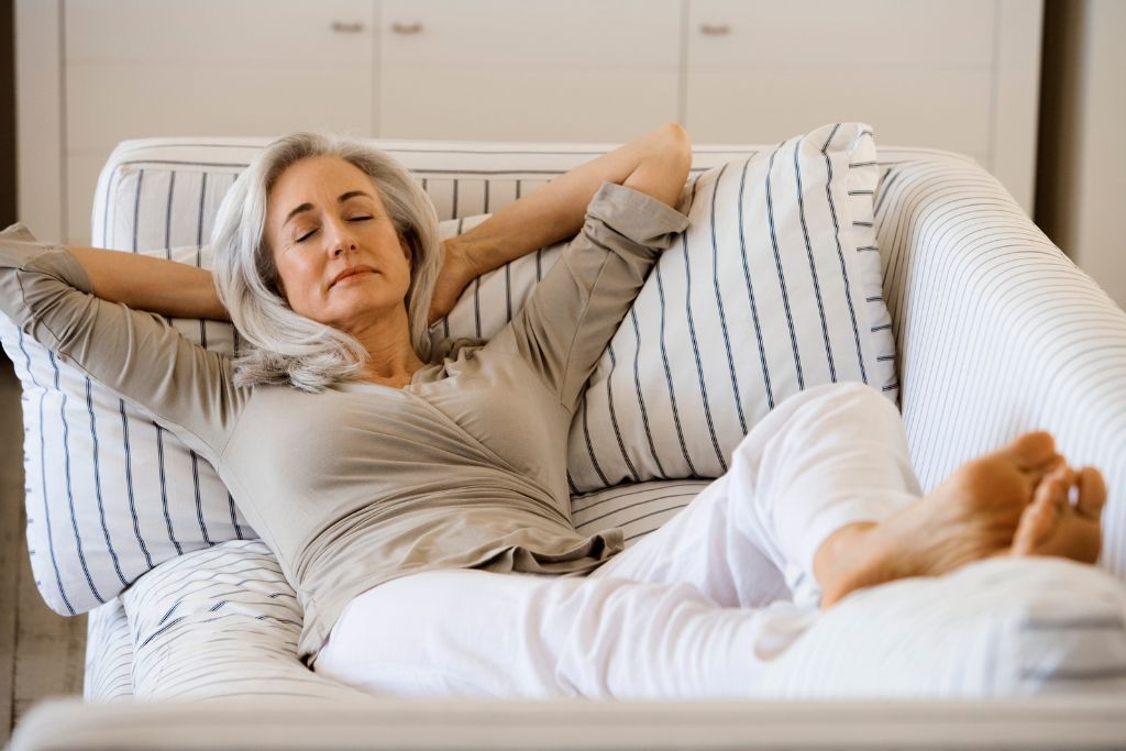 A woman relaxing and sleeping on a couch.