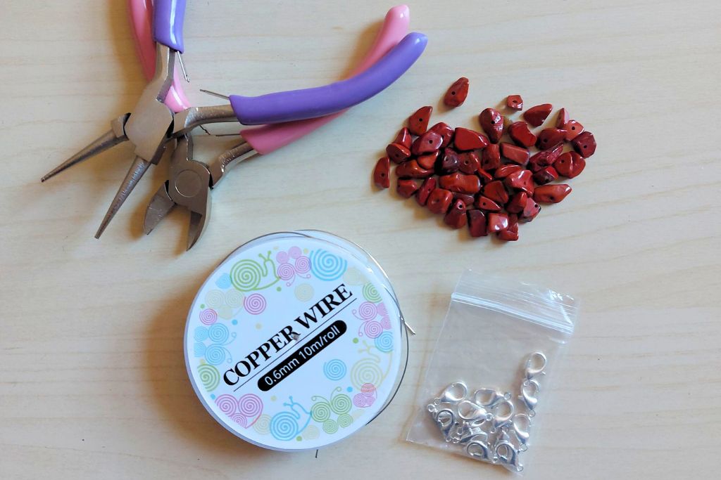 pliers, beads, copper wire, and lock on the table