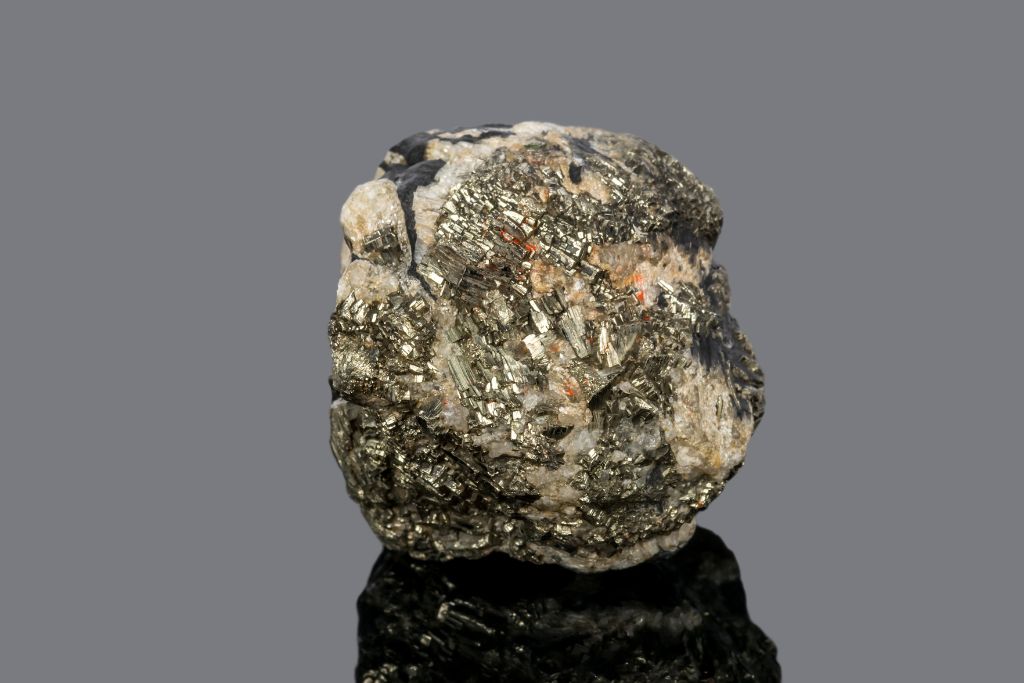 A tinstone or Cassiterite crystal on a black reflective background
