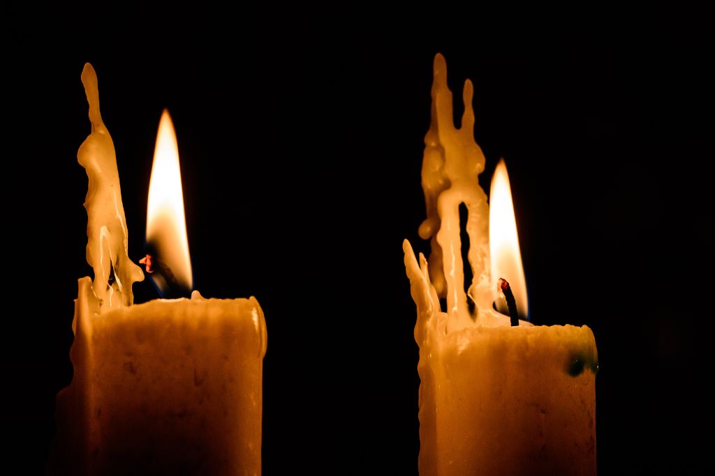 Two candles that are burning on a dark background