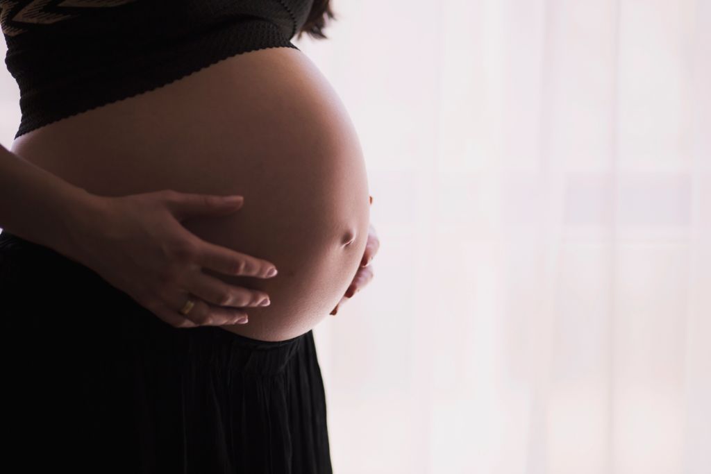 pregnant women showing her baby bump on white background