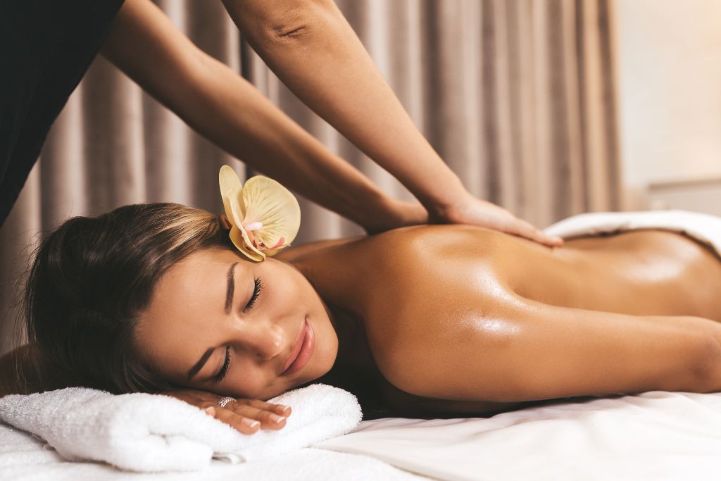 A woman smiling while being massaged in her back