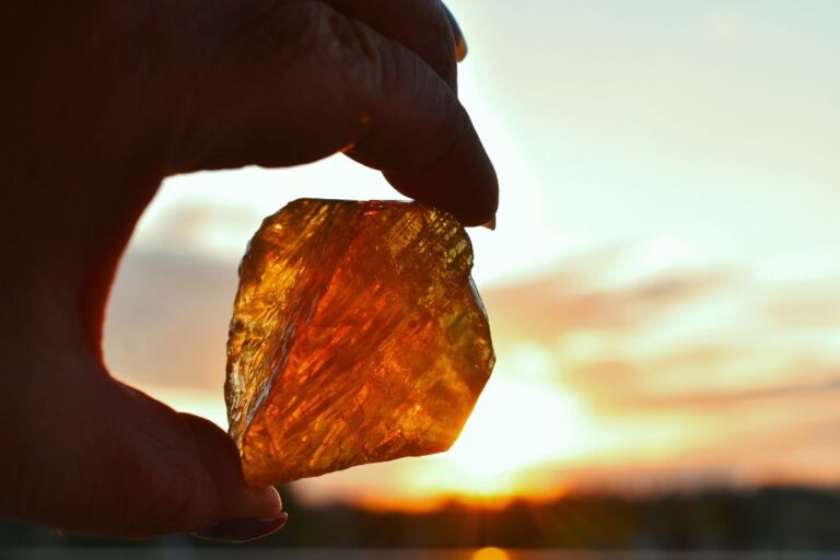 hand holding on her fingertips a yellow crystal on a sunset background