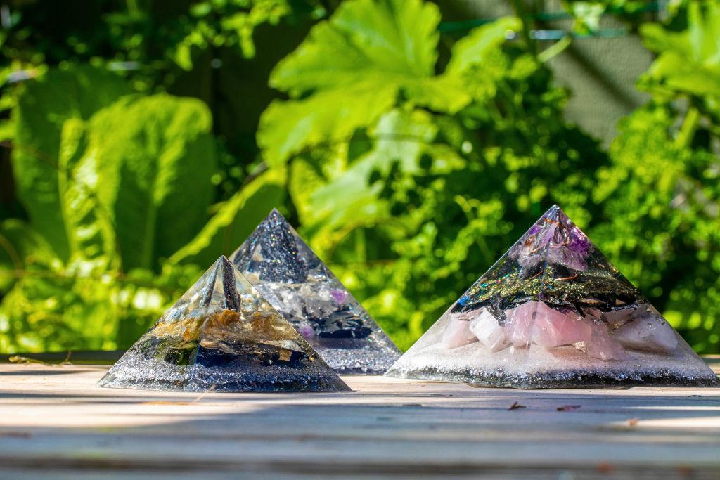 Orgone Pyramids displayed on an outdoor garden with leaves on the background