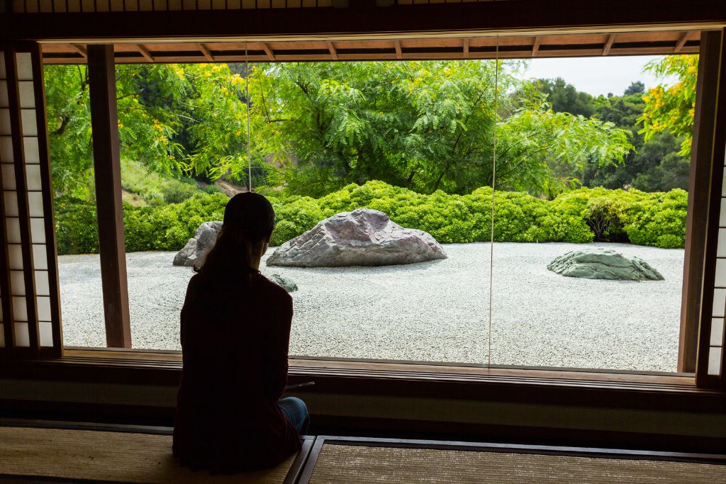 A person sitting Infront of a Zen garden