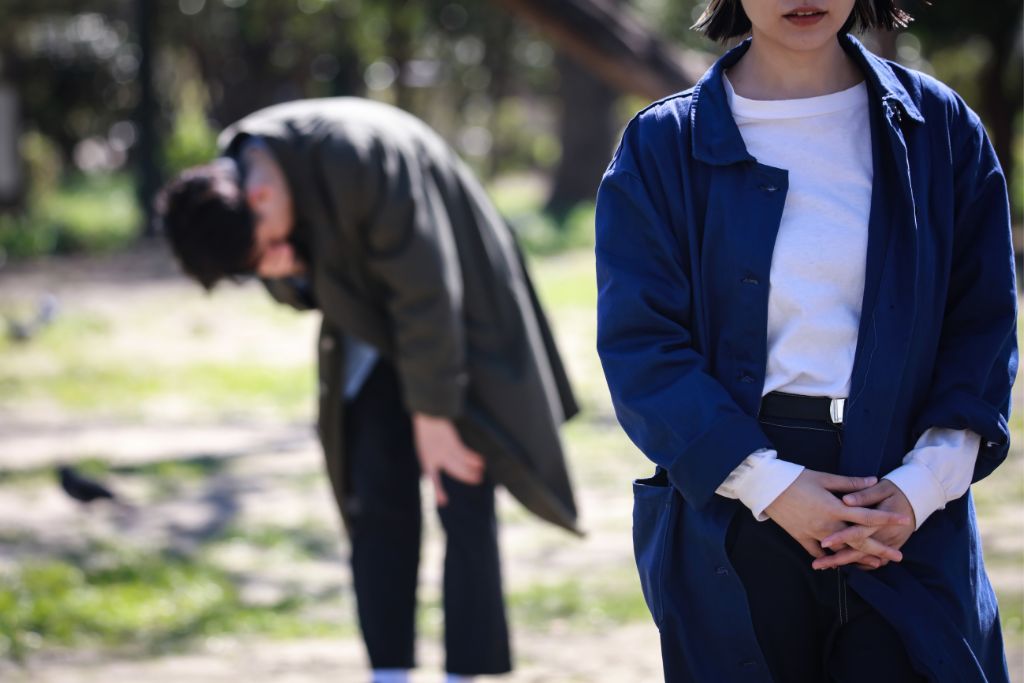 a woman walking away from her crying boyfriend