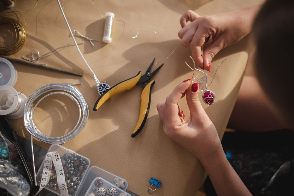 woman doing a crystal pendant necklace using wire and pliers