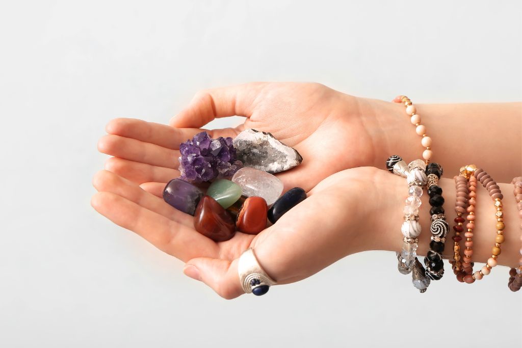 A woman holding different gemstones while wearing crystal bracelet