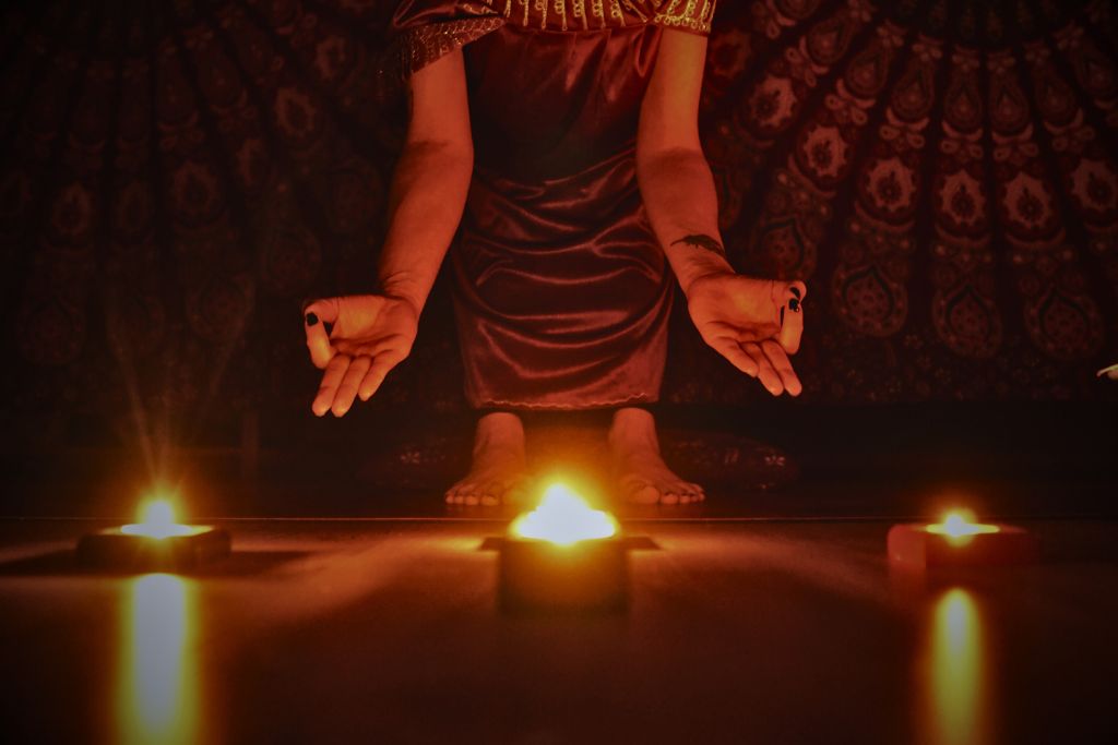 woman doing ritual using three lighted candles placed on the floor