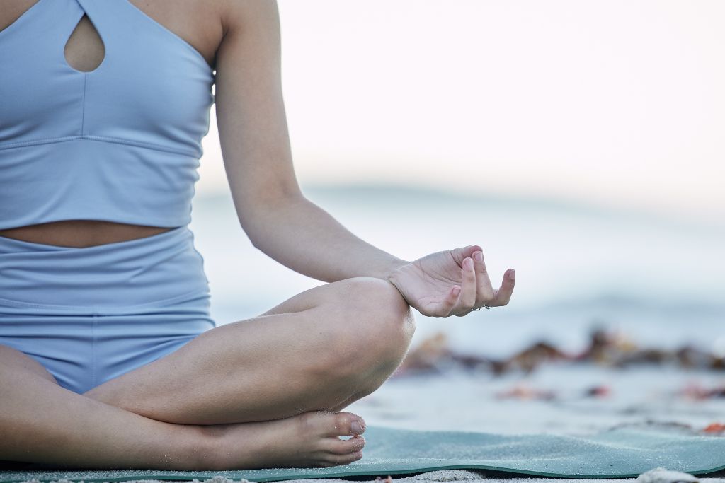 woman meditating on the beach