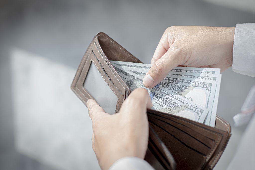 A man holding cash from his wallet