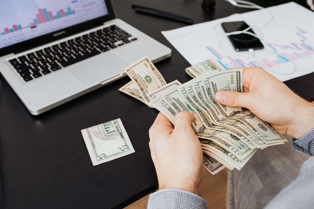 a man counting his money in front of his laptop