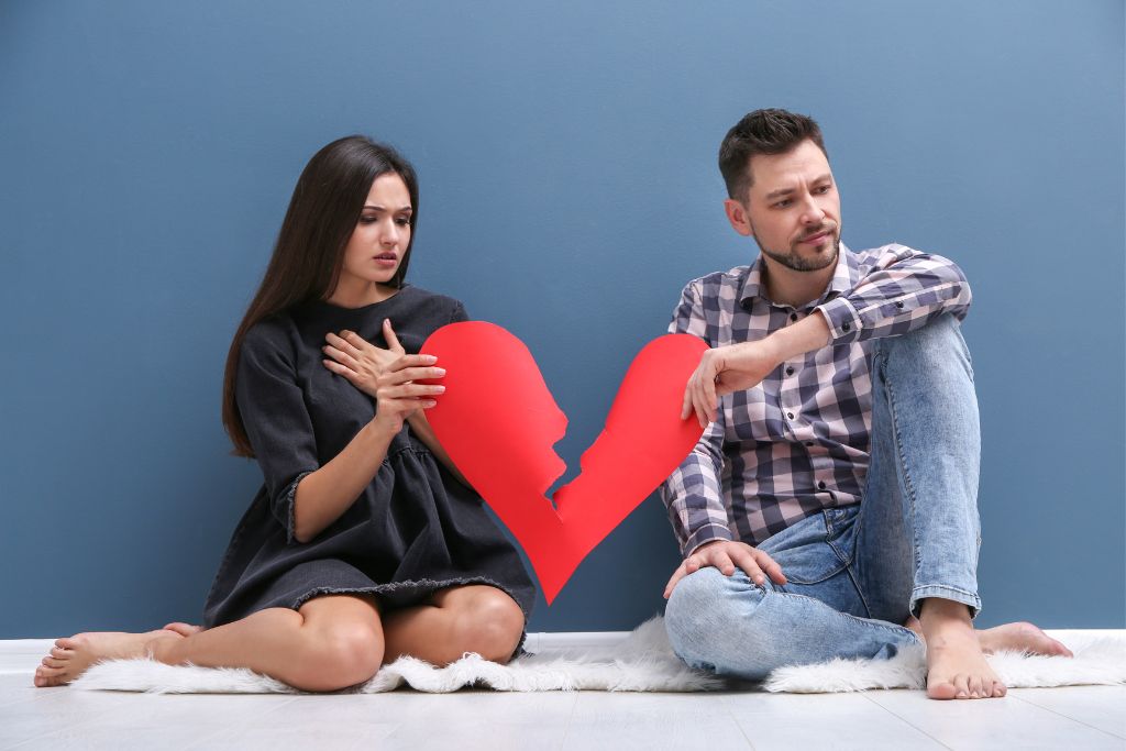 A man and woman holding a teared up paper heart